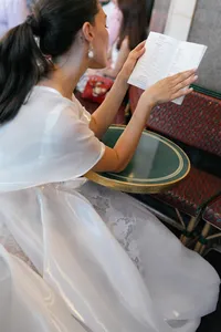 Detail portrait from behind of the bride reading the menu at Café de Flore, highlighting the texture of her gown and the intimate café setting.