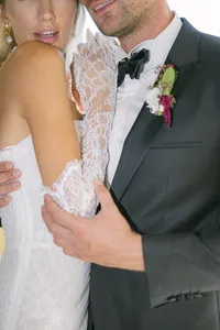 Bride and groom embracing, close-up on the groom’s boutonnière