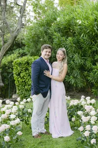 Newly engaged couple embracing among white and pink roses in the gardens of La Chèvre d’Or, Èze
