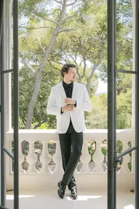 Groom in a white dinner jacket on a balcony before the ceremony
