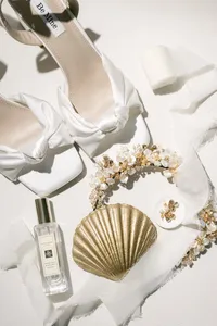 Bridal details with shoes and a seashell on soft fabric