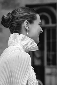 Black and white image of a bride from behind, featuring an elegant updo and a textured, ruffled wedding dress.