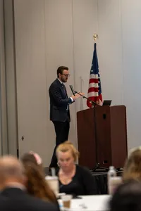 A person in a suit speaking at a podium