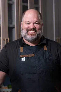 A person in a apron with a big smile on their face