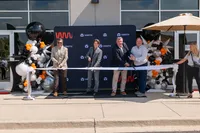 A group of people with large scissors cutting a ribbon