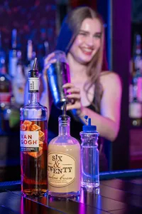 A bartender mixing a drink with the bottles in front of them