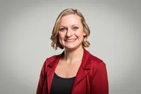 A person in a red blazer smiling