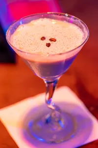 An espresso martini with three espresso beans in the foam