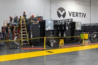 People standing on ladders behind a sectioned off area of a warehouse