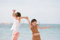 Children holding hands and playing by the ocean at grand hyatt baha mar during a Bahamas beach family photography session