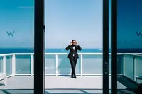Groom posing on balcony for a cinematic shot with ocean in background by Lyndah wells Photography