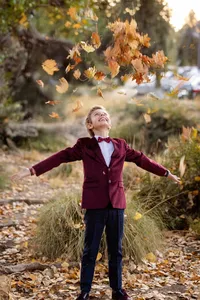 Kid smiling while playing with leaves during a fall family photo session in Orange County