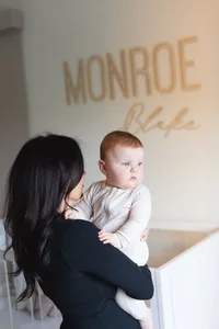 baby looking at the window while on her moms arms during a newborn session in Orange County