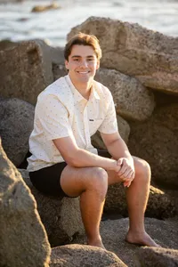 Boy High school senior smiling during a beach graduation photo session in Orange County