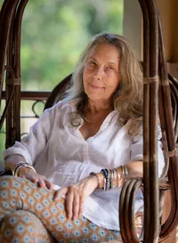 Natural light portrait of Izzy Butterworth seated in a wicker chair, Basunti Yoga Retreat Centre, India.