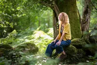 Environmental portrait of Hannah Sherbesky photographed among the trees in a woodland setting.