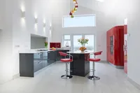 Contemporary kitchen interior with glossy red cabinets, a central island and red bar stools.