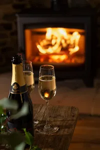 Champagne glasses arranged beside a glowing Hunter Stoves Aspect 7 wood-burning stove.