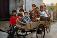 A group of children gathered around a wooden cart on a village street in Punjab, India.