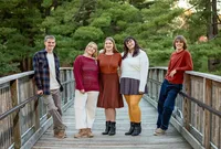 Amelia Island portrait session capturing Edwardsville, Illinois family capturing five siblings on a wooden walkway surrounded by greenery, their autumn-colored outfits and easy smiles reflecting a relaxed, joyful moment.