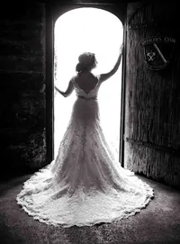 Professional photography by Nature's Child Photography: St. Augustine wedding capturing a bride silhouetted in a historic doorway, her detailed lace train flowing behind as natural light pours in from outside.