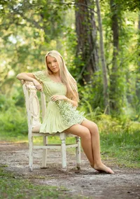 St. Johns senior of a poised high school graduate seated on an antique chair, bouquet in hand, framed by lush greenery and soft natural light in St. Johns, Florida. (Photographed by Nature's Child Photography)