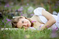Jacksonville, FL portrait session capturing a St. Johns graduating senior nestled among blooming wildflowers, her gentle expression and golden light evoking a timeless, storybook feel. - a Nature's Child Photography Senior Photo Experience
