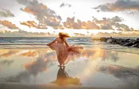 Jacksonville, FL portrait session capturing At sunrise on Vilano Beach, a graduating senior twirls in the tide’s reflection, her dress catching the breeze as pastel clouds and early light wrap the moment in quiet anticipation.