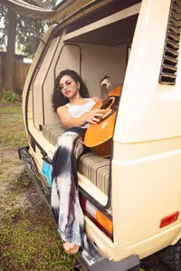 Jacksonville portrait session capturing Orange Park senior of a high school graduate seated in a vintage van, guitar in hand, blending artistic expression with effortless, free-spirited style. - a Senior Portrait Experience by Nature's Child Photography