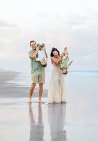 Jacksonville, FL portrait session capturing Beach, parents playfully lift their two little ones upside down, bare feet in the wet sand during a lively family.session with Nature's Child Photography.