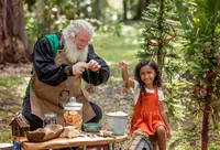 Child and Santa create pinecone bird feeders together during a Santa's Enchanted Forest photography session in St. Johns, Florida with Nature's Child Photography, surrounded by woodland Christmas decorations, nature-inspired activities, and outdoor holiday magic.
