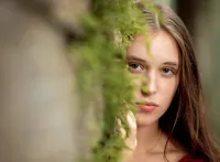 High school senior in St. Augustine, gazes softly through cascading greenery, creating an intimate and timeless outdoor photograph. (Photographed by Nature's Child Photography)