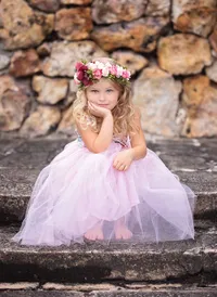 Jacksonville, FL portrait session capturing a thoughtful young princess in a pastel tulle dress and floral crown as she sits on rustic stone steps during a signature fairy adventure session in Palatka.