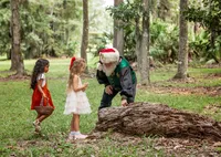 Children explore the woodland with Santa during a Santa's Enchanted Forest photography session in St. Johns, Florida with Nature's Child Photography, discovering nature together among towering trees, forest trails, and outdoor Christmas magic.