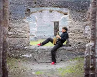Professional photography by Nature's Child Photography: Senior musician sits in the weathered stone window of the Sugarmill Ruins in St. Mary’s, Georgia, playing saxophone in a dramatic outdoor senior photo session.