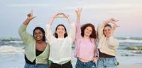 Four high school senior best friends celebrate their final year together by spelling “LOVE” with their arms at sunset in Vilano Beach. - A portrait experience by Nature's Child Photography.