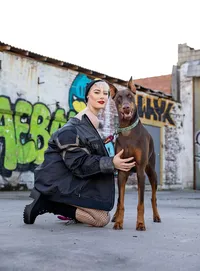 High school senior, kneels confidently beside her Doberman in a vibrant graffiti-covered urban alley, blending strength and style. - A portrait experience by Nature's Child Photography.