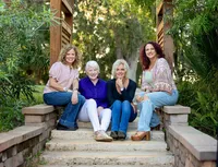 Jacksonville, FL portrait session capturing Palm Coast, family of an older mother sitting between her three adult daughters on garden steps, their close posture and easy smiles reflecting a multigenerational moment.