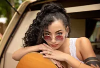 Professional photography by Nature's Child Photography: Orange Park, senior leans over her guitar with rose-tinted glasses and effortless poise, creating a bold, music-inspired senior full of personality.