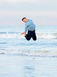 Tween boy leaping high above the waves during a beach family portrait session. (Photographed by Nature's Child Photography)