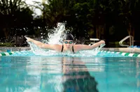 Professional photography by Nature's Child Photography: Focused high school senior in St. Johns explodes through the water in a butterfly stroke, arms extended and determination visible in this dynamic sports potrait session.
