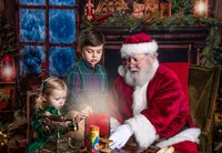 Children gathered around a glowing magical lantern with Santa during a Santa’s Magical Christmas photography session in Jacksonville, Florida with Nature’s Child Photography, cozy holiday decor and warm candlelight creating a storybook Christmas scene.