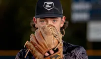 Ponte Vedra portrait session capturing a determined tween baseball player in O’Fallon, Illinois peering over his well-used glove, eyes sharp and focused during a dramatic sunset sports session.