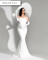 Fitted white maternity gown with thin straps, draped neckline, and flared skirt, styled with long white gloves.