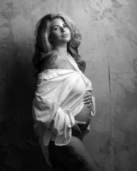 black-and-white editorial maternity portrait of sexy pregnant mom in open white shirt touching her belly