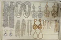 Drawer displaying silver and gold statement earrings with rhinestones, pearls, and dangling chains.