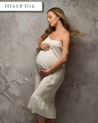 White linen tea length maternity dress with spaghetti straps and ruffled detail along the bottom.