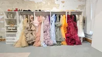 Colorful maternity gowns hanging beside the open photography area in Kelsey Freeman’s studio.