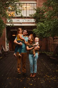Happy candid family of four holding their children outside at Ponce City Market in Atlanta, Georgia.