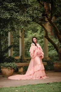 Pregnant woman in a pink ruffled dress at Cator Woolford Gardens with columns in the background.
